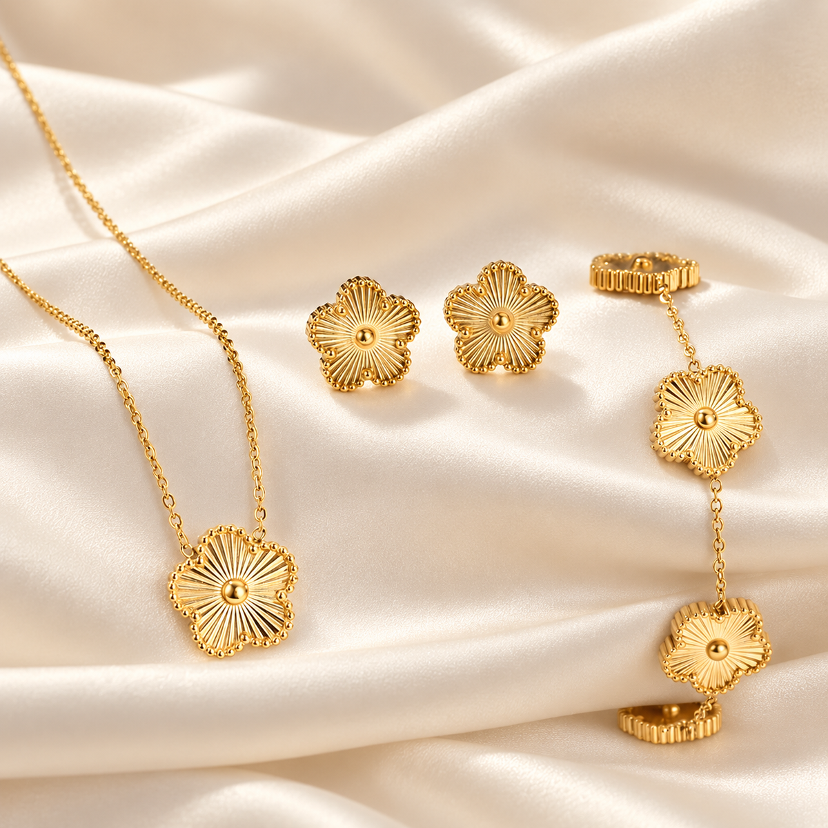 Parure dorée à fleurs : collier, bracelet et boucles sur satin